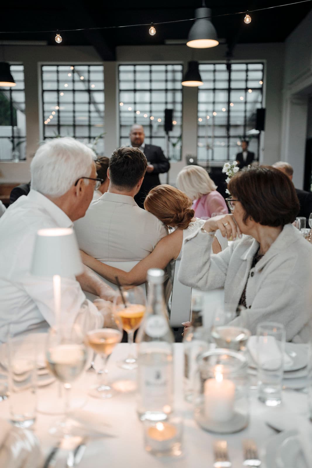 Hochzeitsgäste an der festlich gedeckten Tafel mit Kerzen und Gläsern