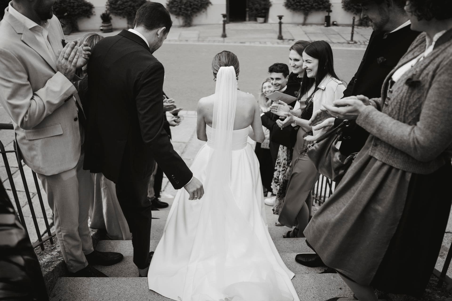 Braut wird von Gästen im Freien beglückwünscht – von hinten fotografiert