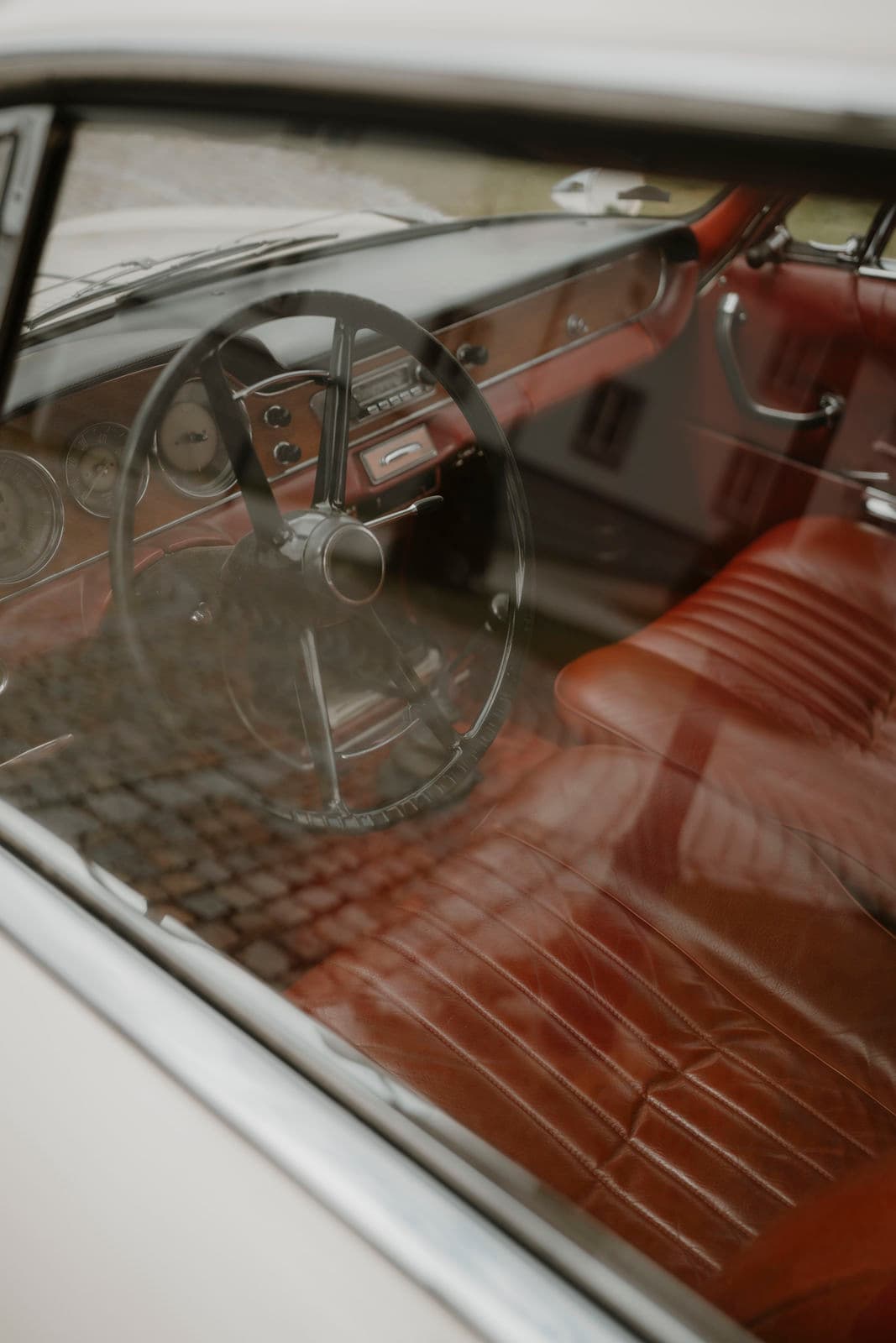 Innenraum eines Oldtimers mit rotem Leder und Lenkrad – Detailaufnahme