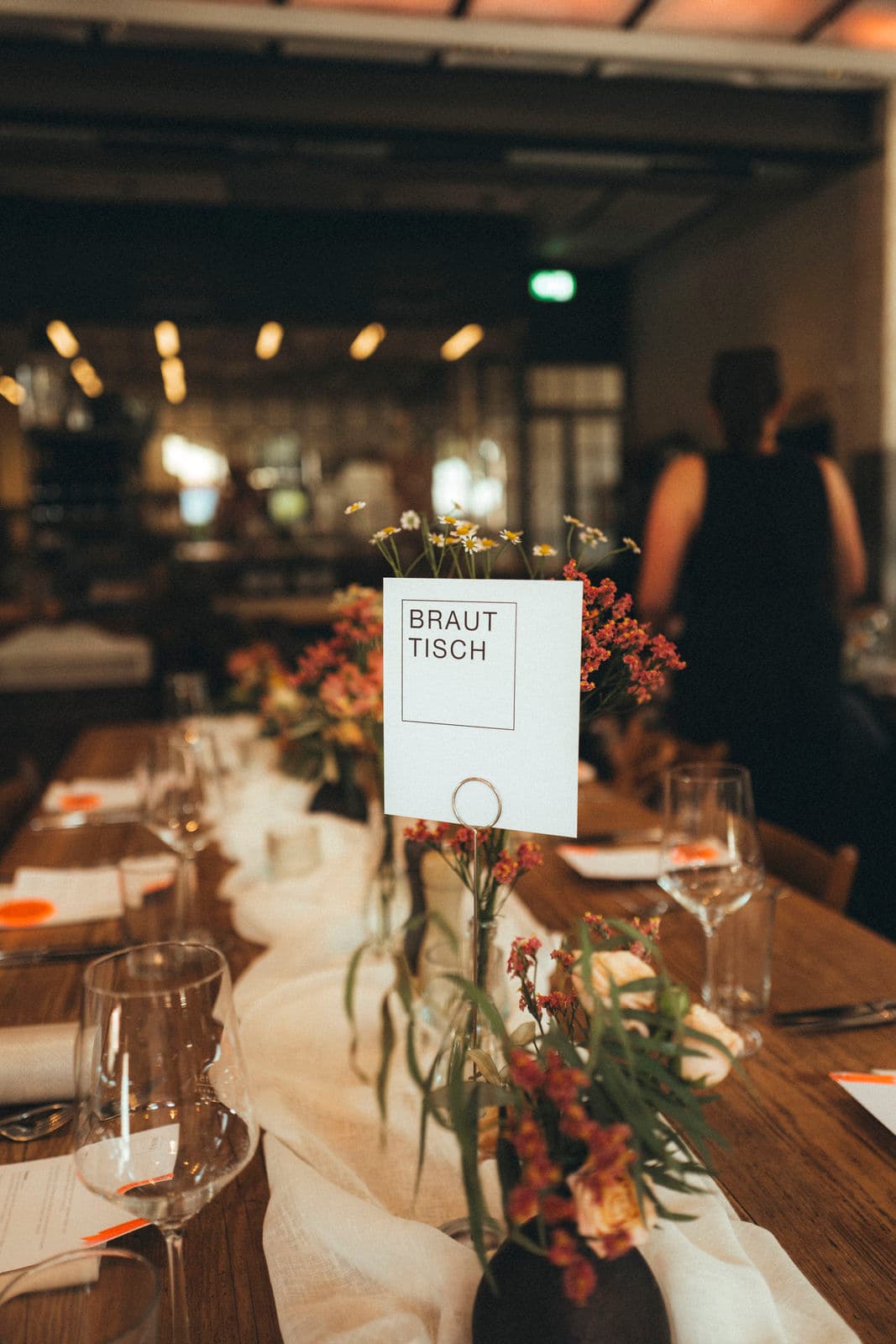 Brauttisch mit Blumendekoration und Namensschild im Restaurant