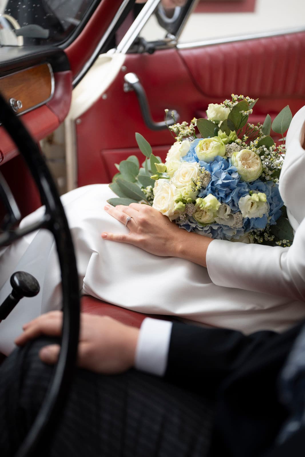 Blau-weißer Brautstrauß auf dem Lenkrad des Oldtimers – Detail