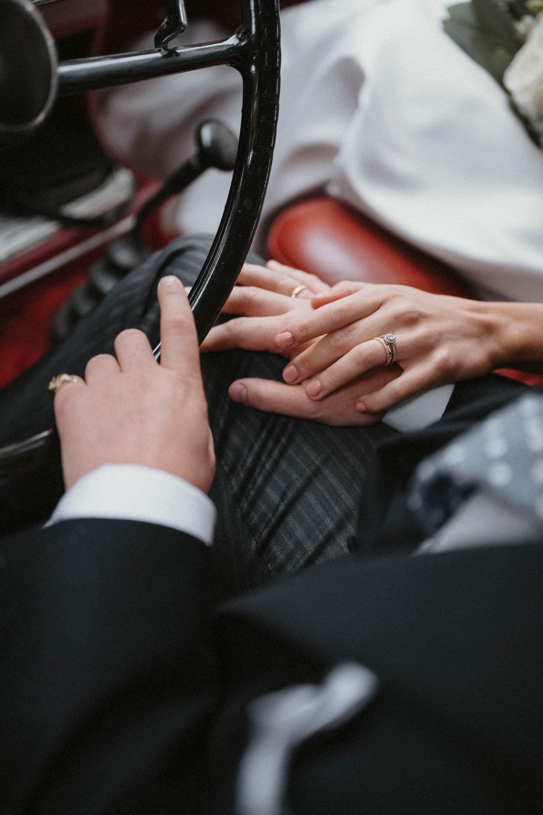 Hände des Brautpaars mit Ehering am Lenkrad des Oldtimers – Detail