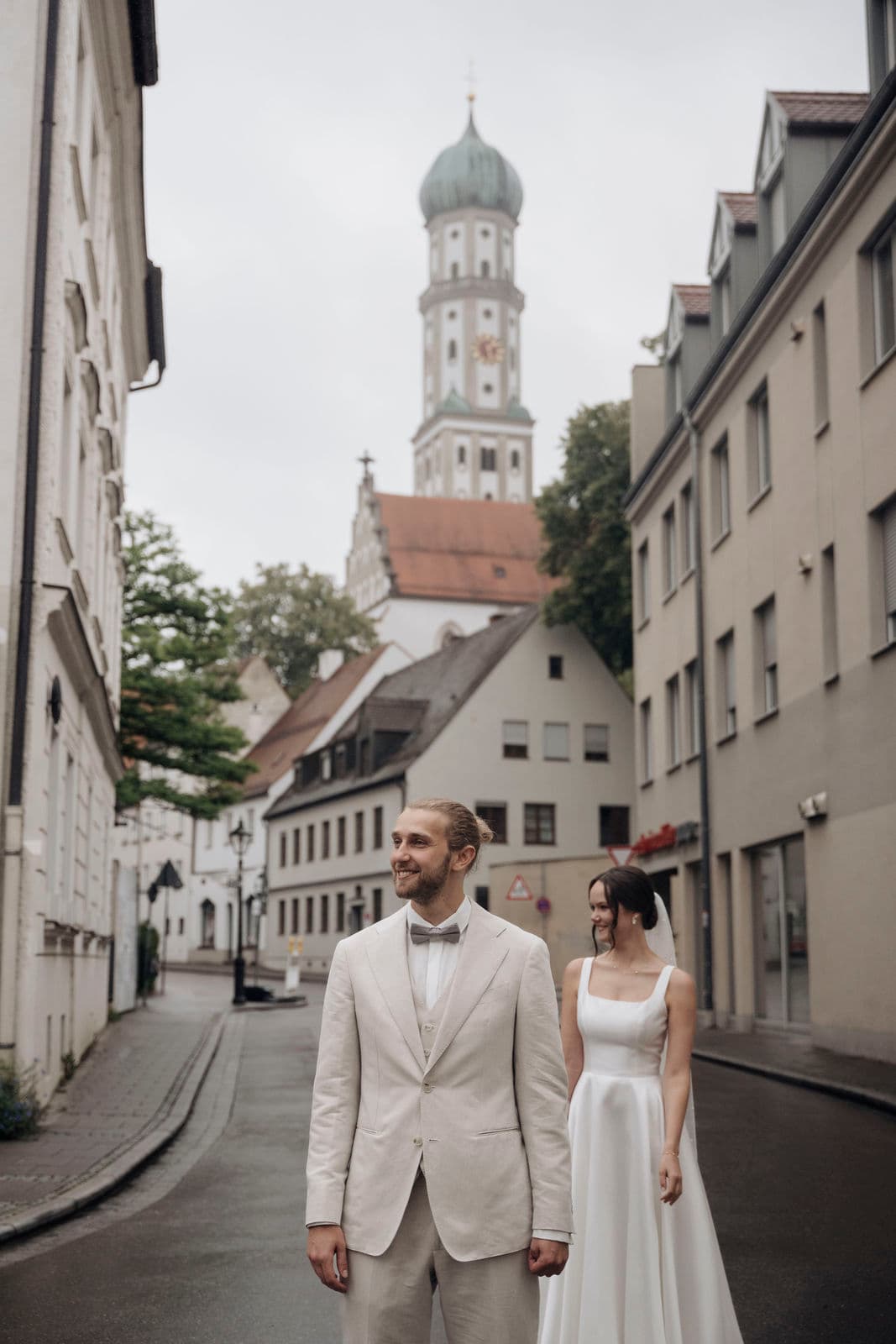 Braut tritt beim First Look hinter den Bräutigam, dahinter ragt der Zwiebelturm der Stadtkirche auf