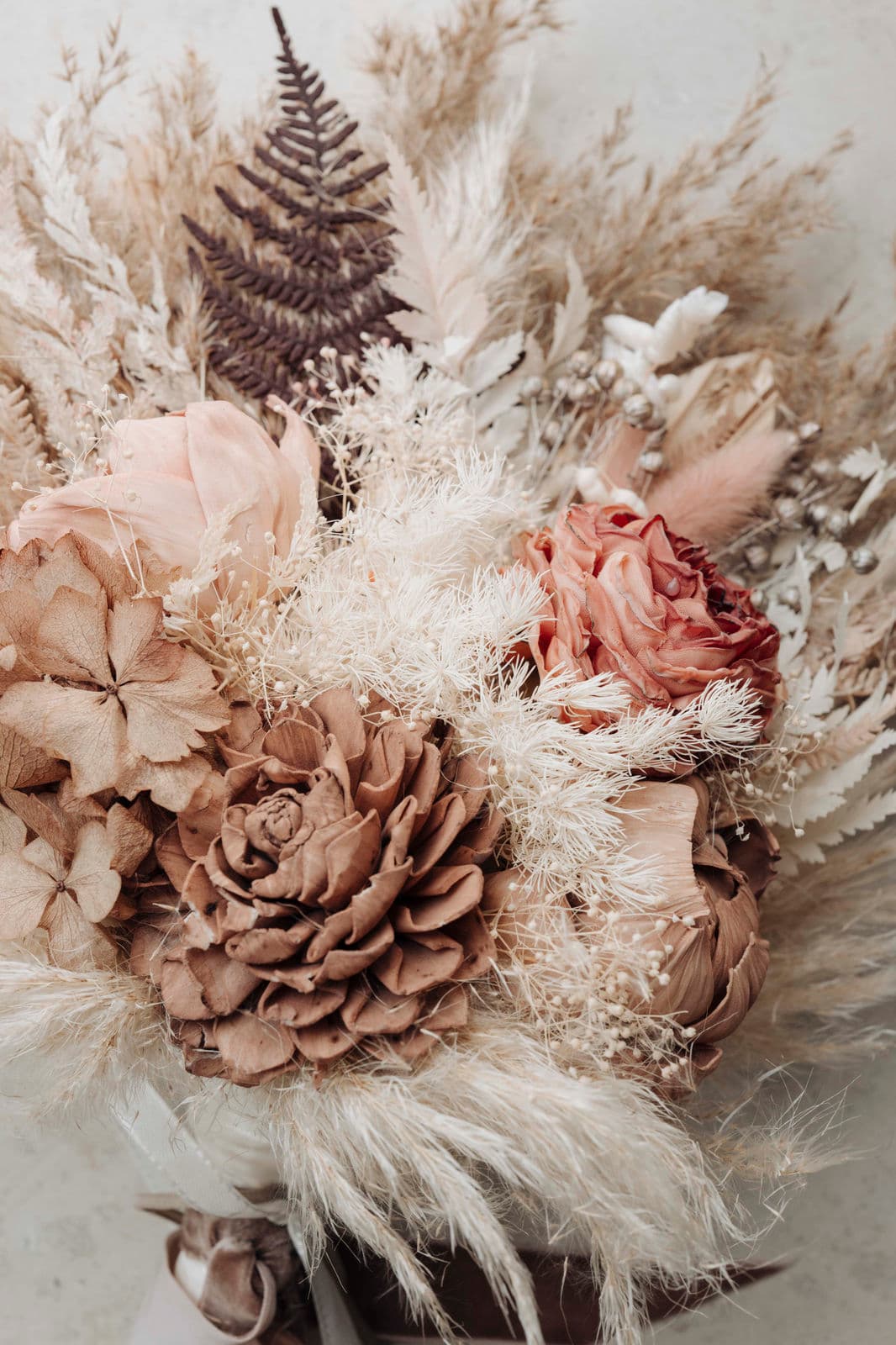 Boho-Brautstrauß aus Trockenblumen mit Pampasgras, Farn und Rosen in Rosé- und Beigetönen